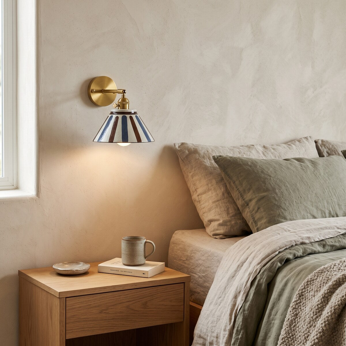 Birk ceramic wall light in Sunburst Lines glowing above an oak bedside table