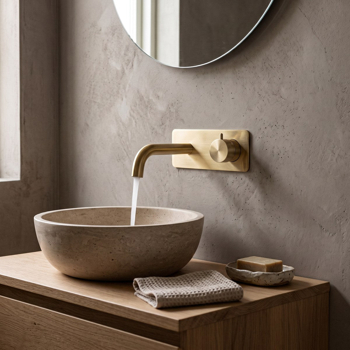 Cavion brushed gold wall tap running into a stone basin on an oak vanity