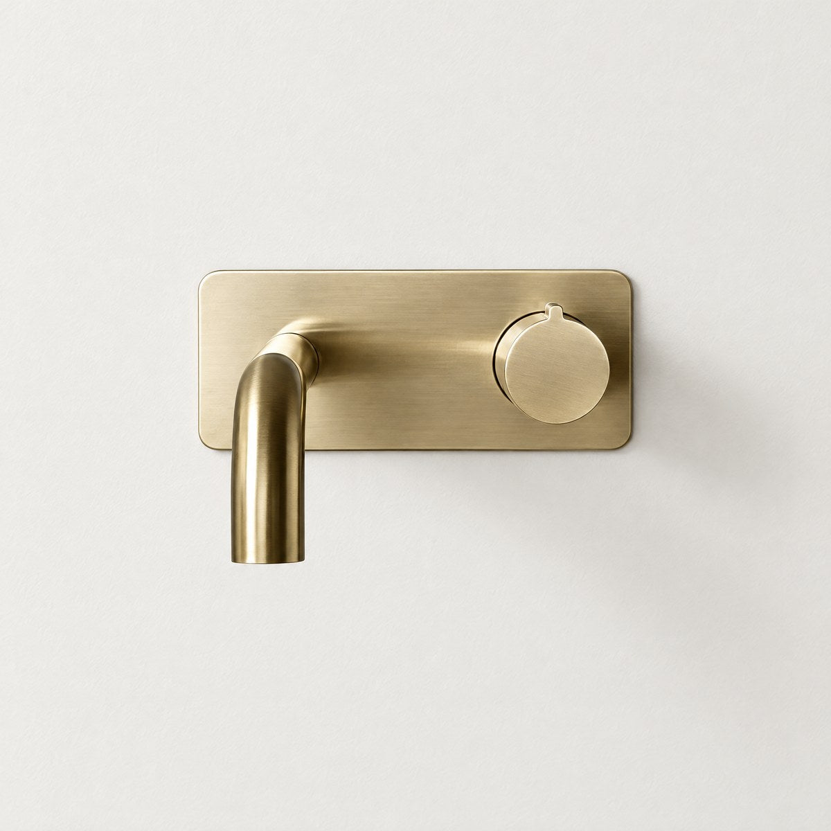 Cavion wall-mounted basin mixer tap in brushed gold on an off-white wall