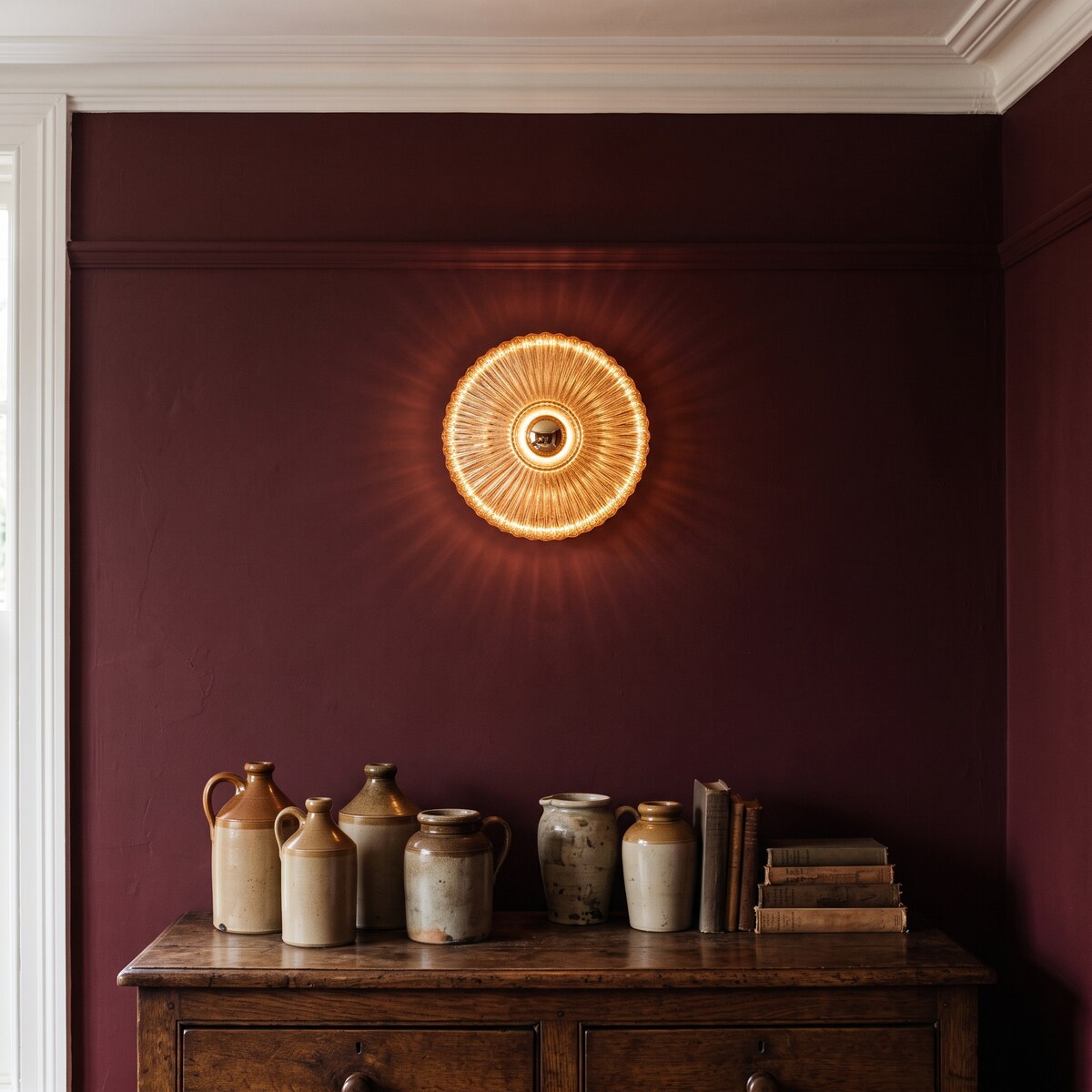 Dahlia amber glass wall light glowing on a claret-red dining-room wall