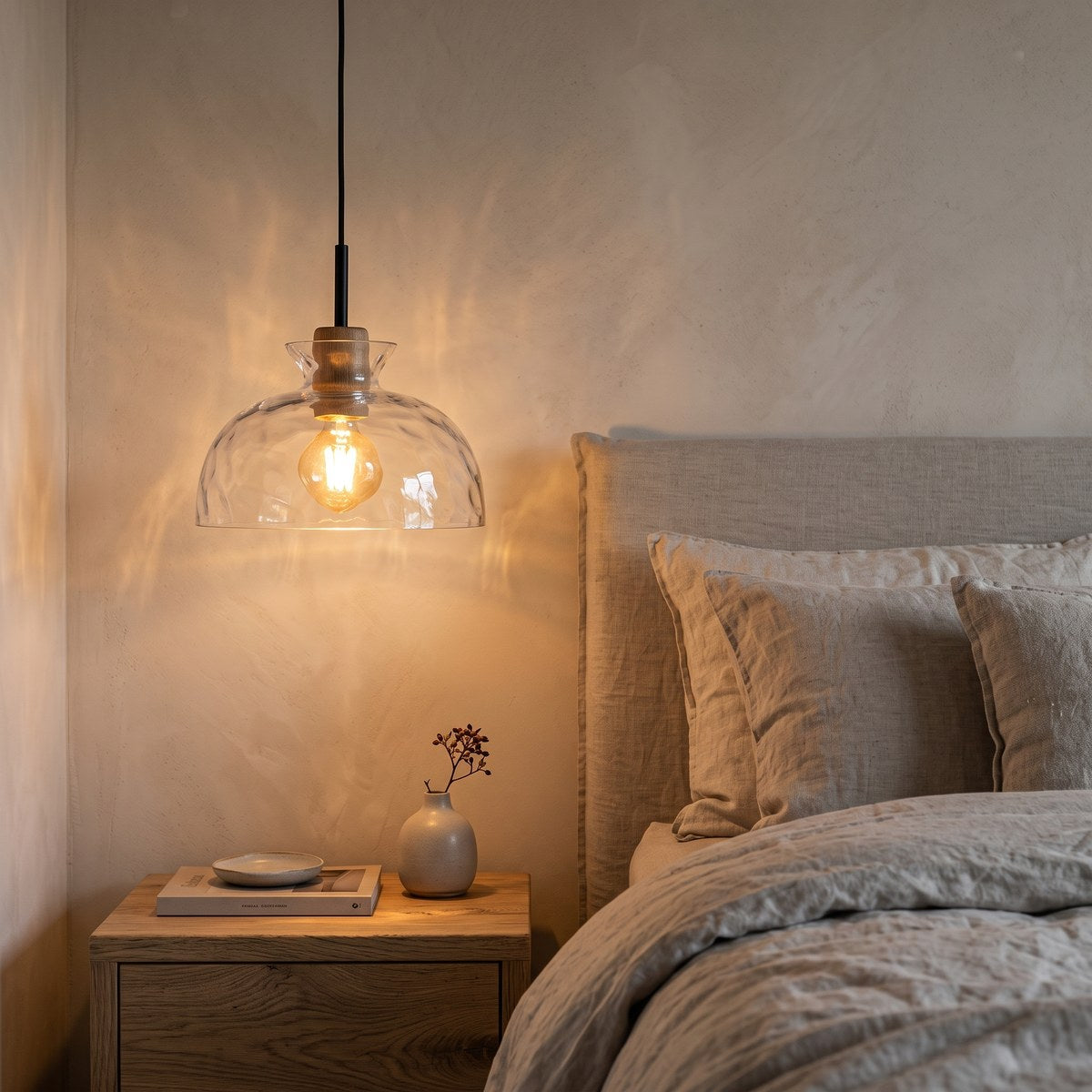 Fjord bowl pendant light hanging beside a linen bed above an oak bedside table