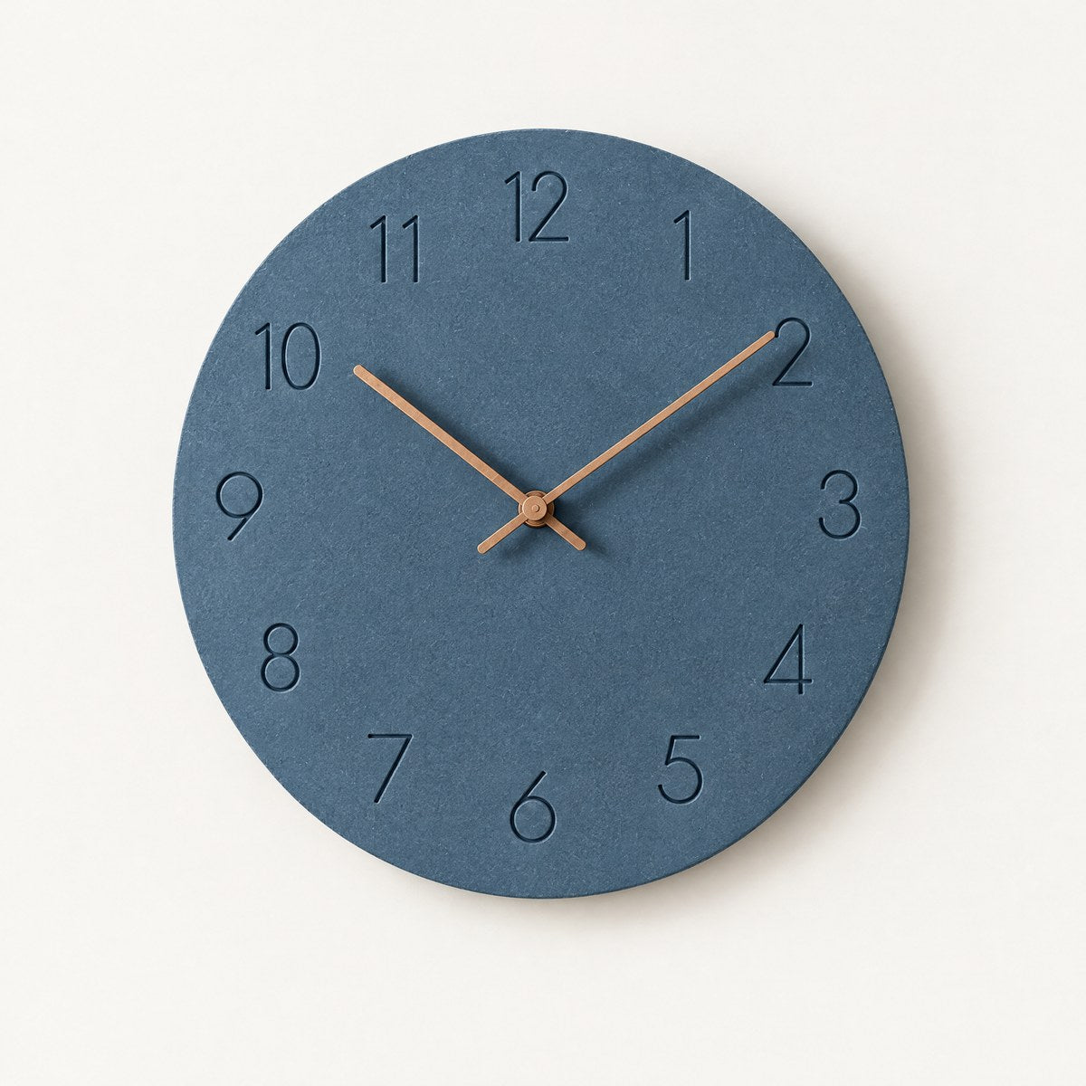 Hora minimalist silent wall clock with dusty blue face and copper hands on a white wall