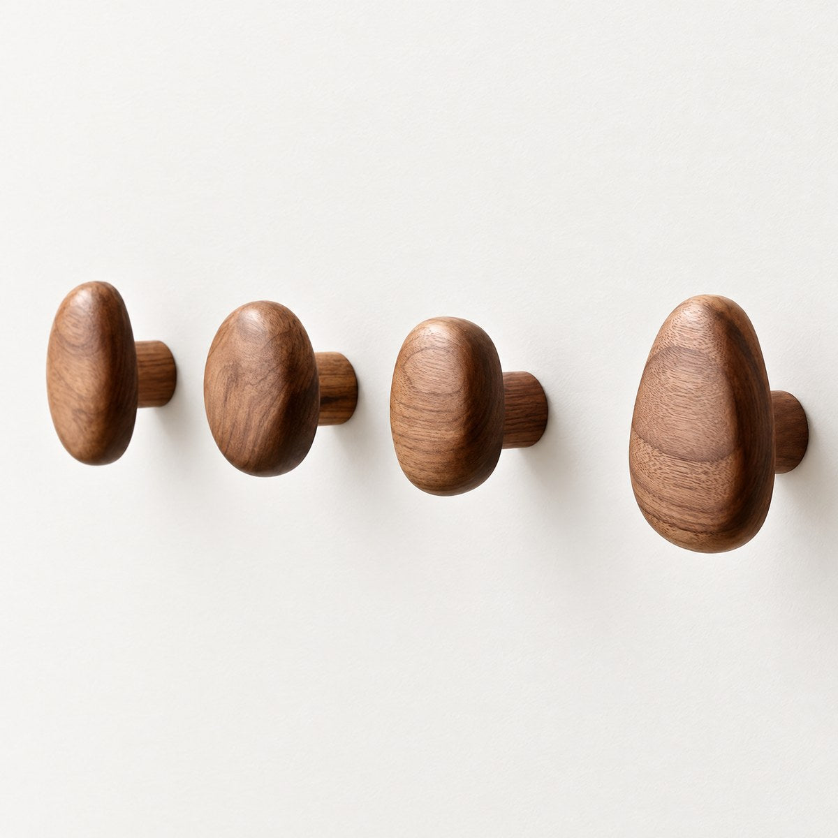 Kiyo set of four walnut pebble wall hooks on an off-white wall