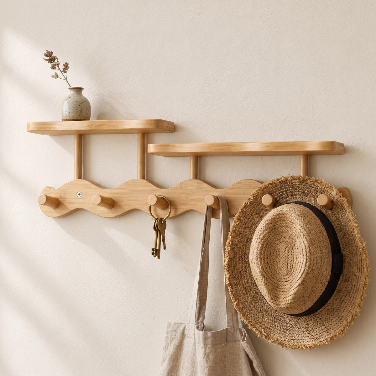 Close-up of the Onda oak coat rack's wavy bamboo board and round pegs with keys, tote and straw hat
