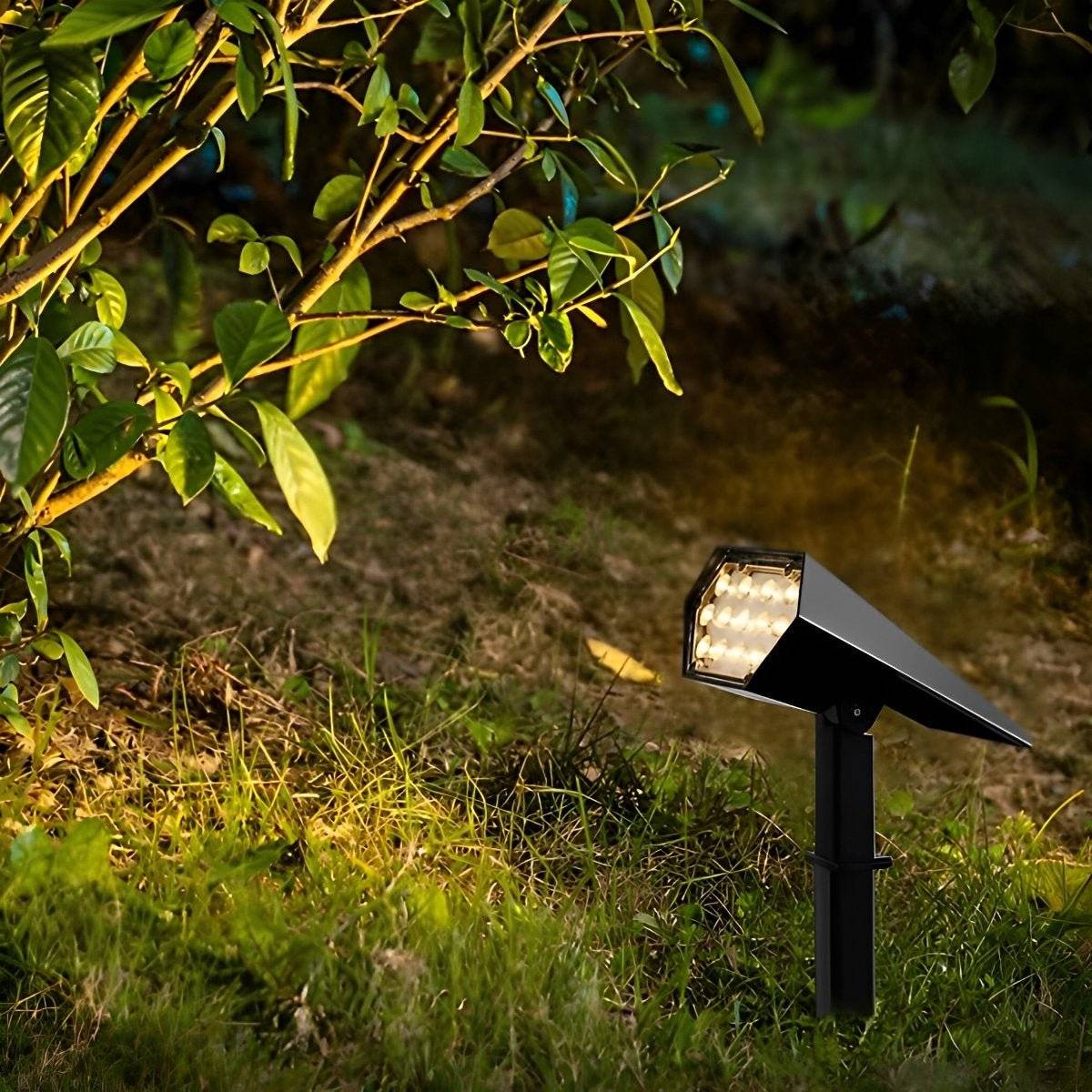Sunpeak solar spotlight glowing warm white in a planted garden border