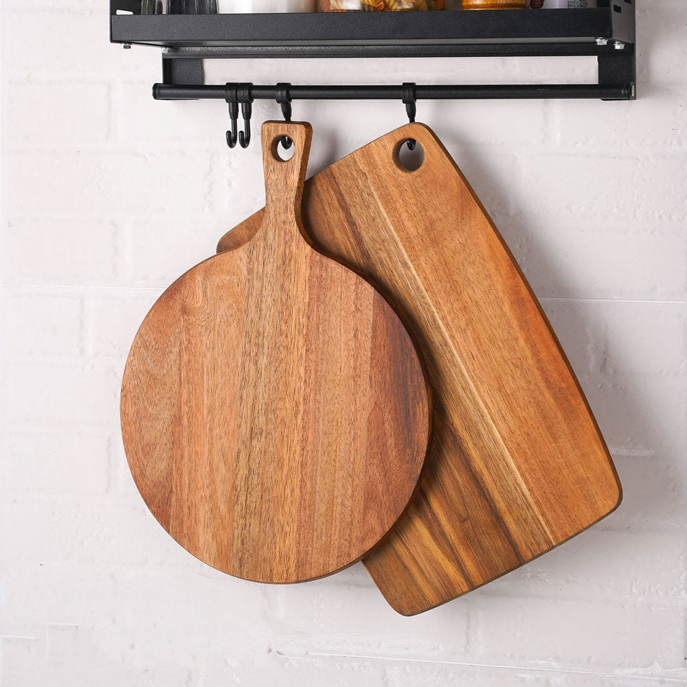 Two wooden cutting boards hanging on a magnetic strip against a white tiled wall.