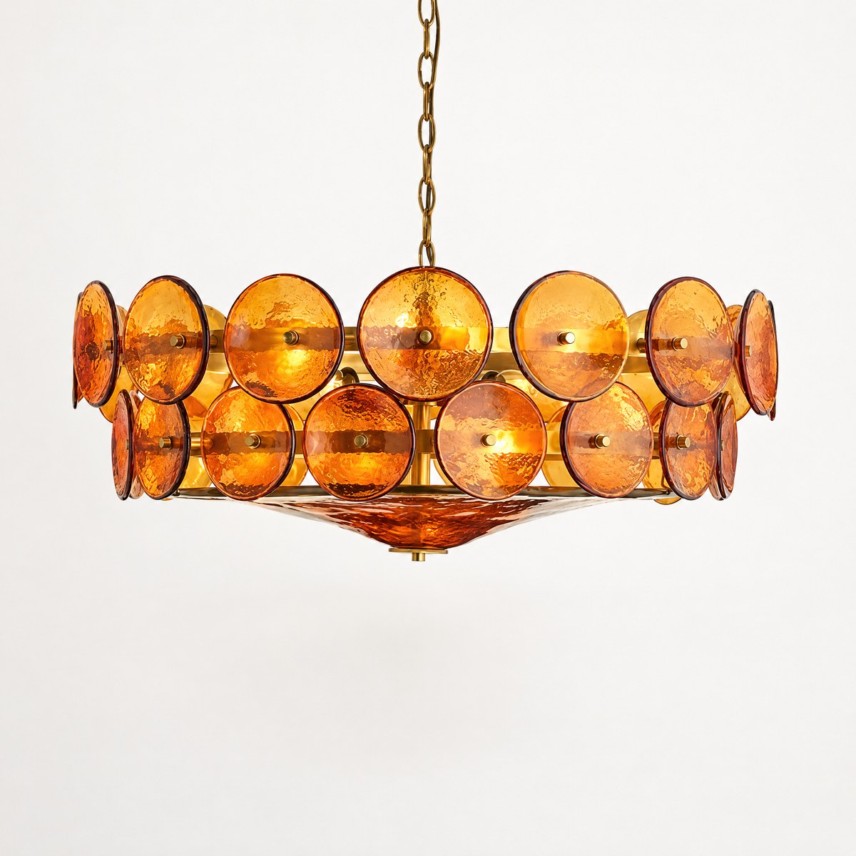 Ambra chandelier of overlapping amber glass discs on a brass frame, lit