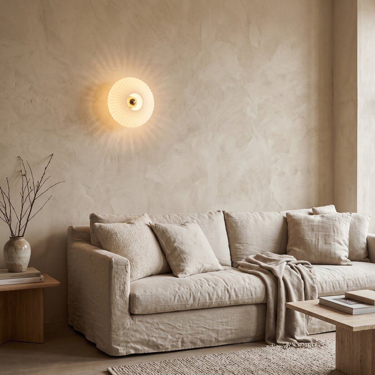 Dahlia milky white glass wall light glowing above a linen sofa
