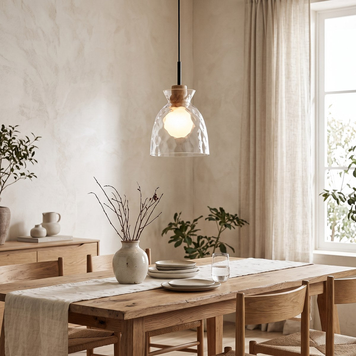 Fjord rippled glass pendant light glowing above an oak dining table