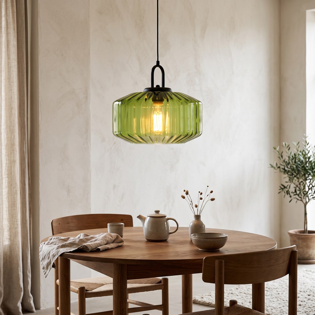 Riva green ribbed glass pendant light glowing above an oak dining table