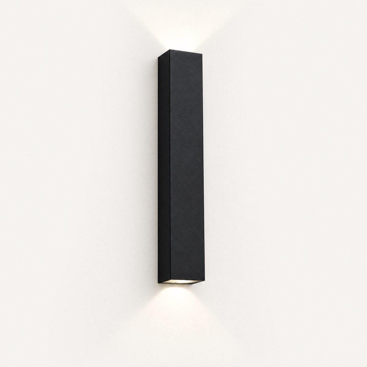 Totem black up and down outdoor wall light casting beams of light on a white wall