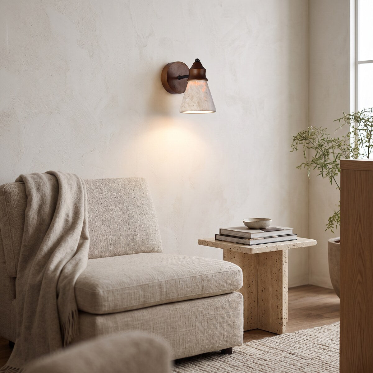 Tufa travertine wall light above a linen armchair in a reading corner