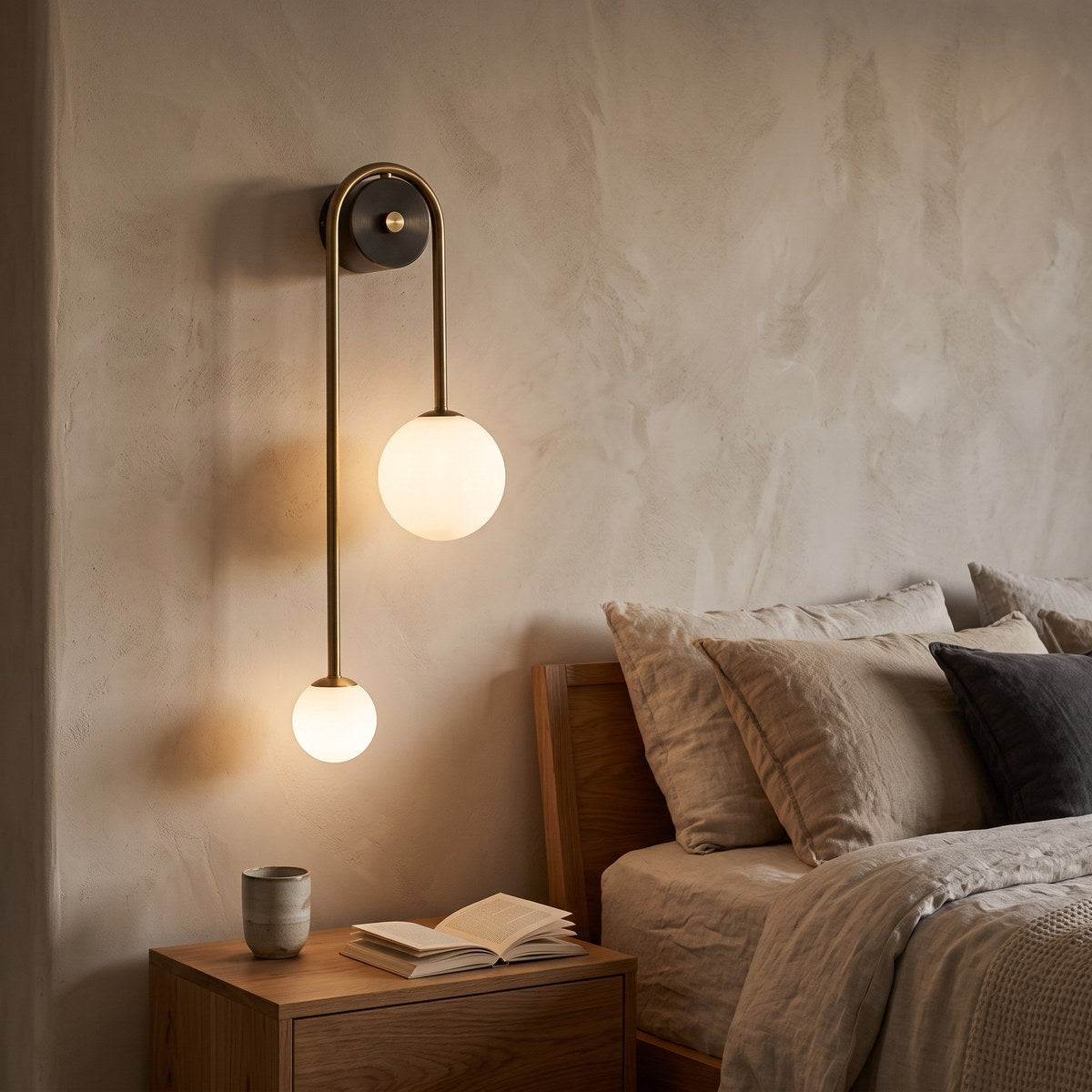 Vionessa brass globe wall light glowing beside a linen bed and oak bedside table