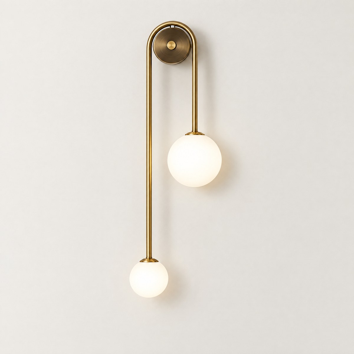 Vionessa brass loop wall light with two opal glass globes, lit, on an off-white wall